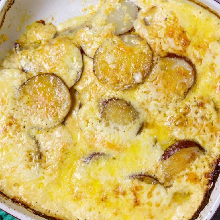 A casserole dish filled with potatoes baked in a cheesy sauce.
