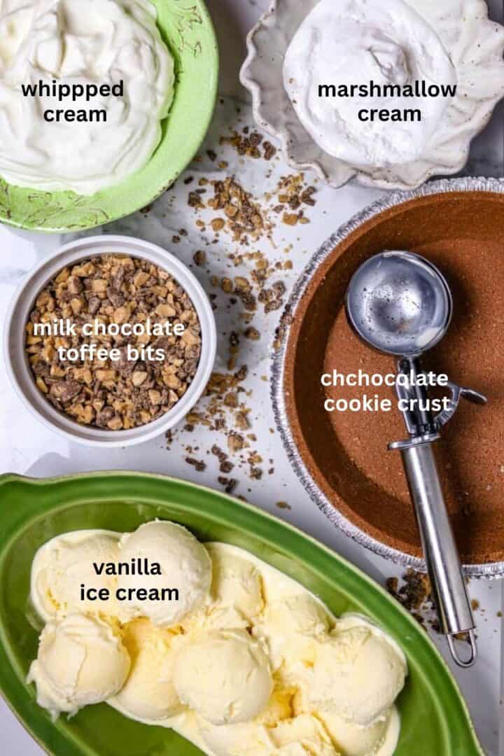 Ingredients of a chocolate cookie pie crust, vanilla ice cream, whipped ream, marshmallow cream, and chocolate toffee bits on a counter top.