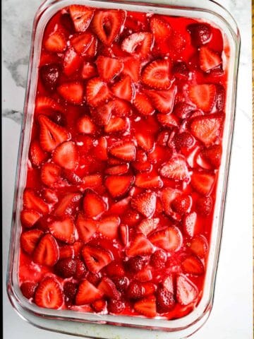 A glass casserole dish of strawberries and jello.