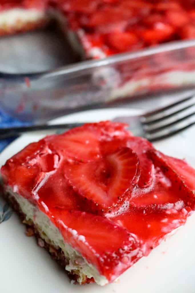 A plated serving of Strawberry Pretzel Salad and a whole dish.