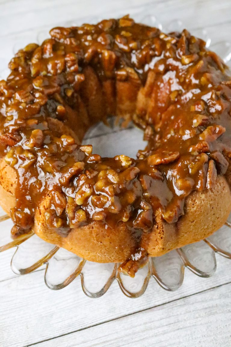 A 2-Ingredient Pumpkin Cake With Brown Sugar Glaze on a glass cake plate.