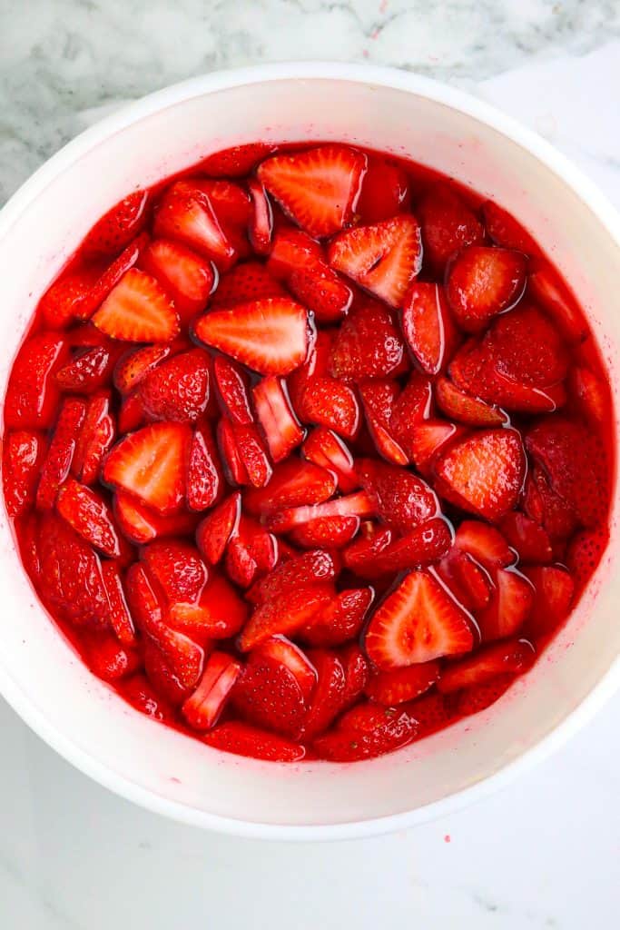 A bowl of sliced strawberries and jello.