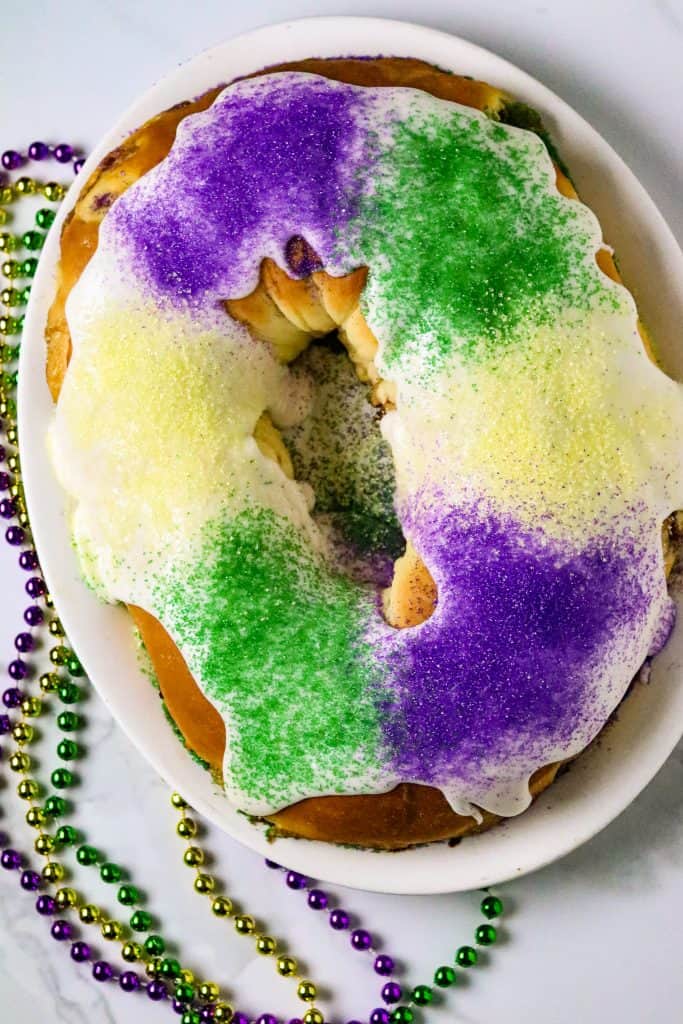 A King Cake with colored sugars of purple, green, and gold for Mardi Gras Food Recipes.