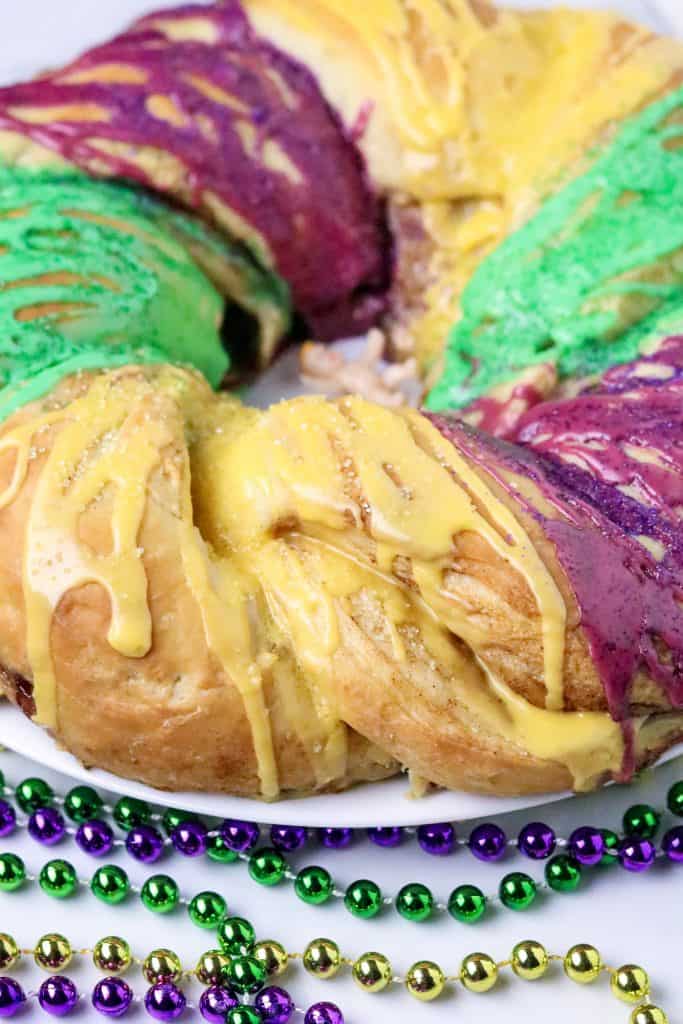 A braided King Cake baked an d iced with purple, green, and gold icing.