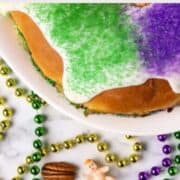 A plastic baby, half of a pecan, and a kidney bean surrounded by beads next to a cake.