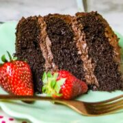 A slice of chocolate cake with fresh strawberries on the plate.