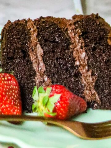 A slice of chocolate cake with fresh strawberries on the plate.