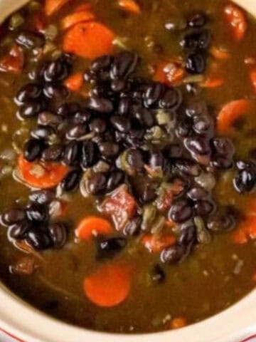 A pot of black bean soup with carrots.