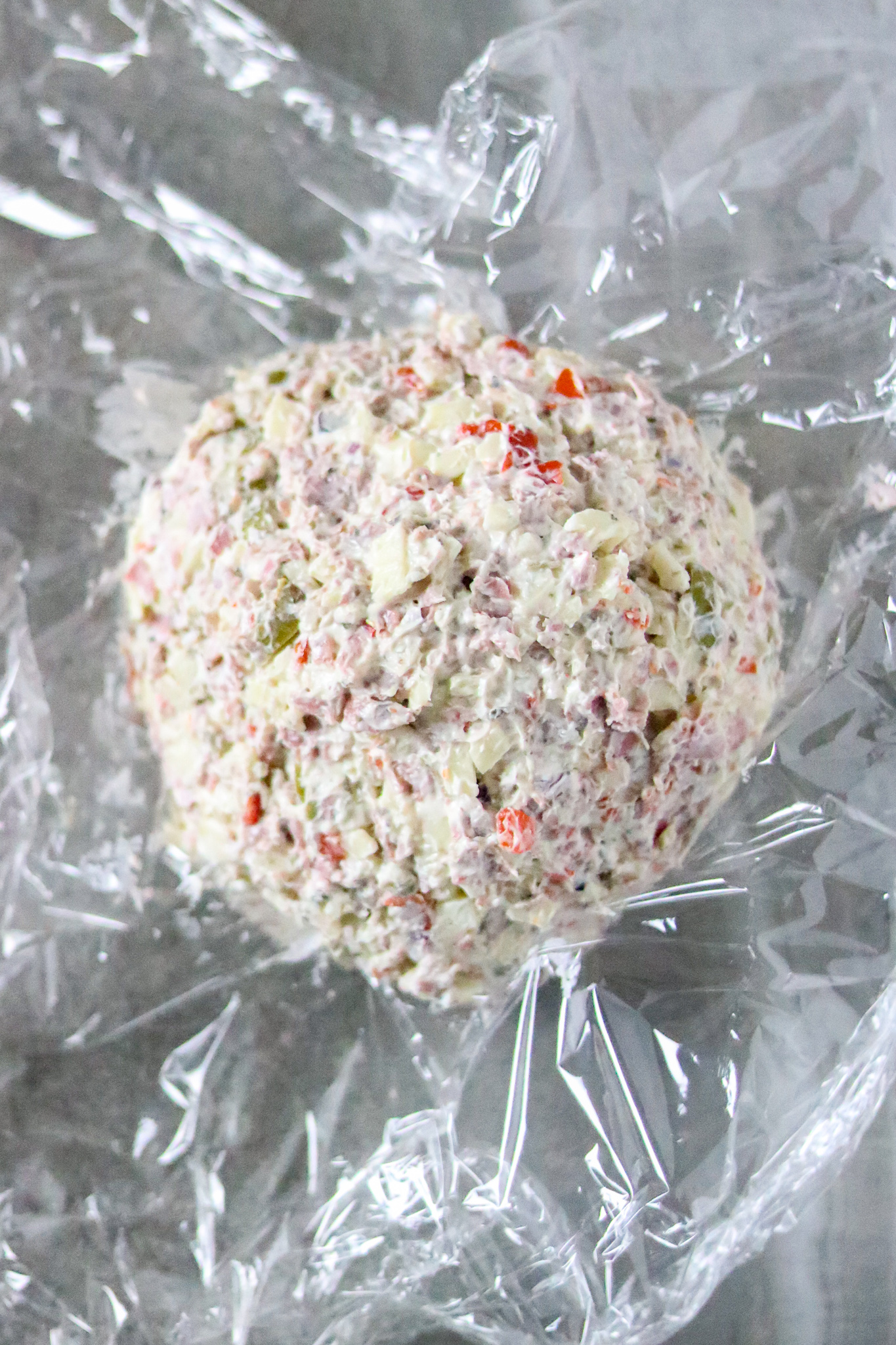 A cheese ball on a piece of plastic wrap.