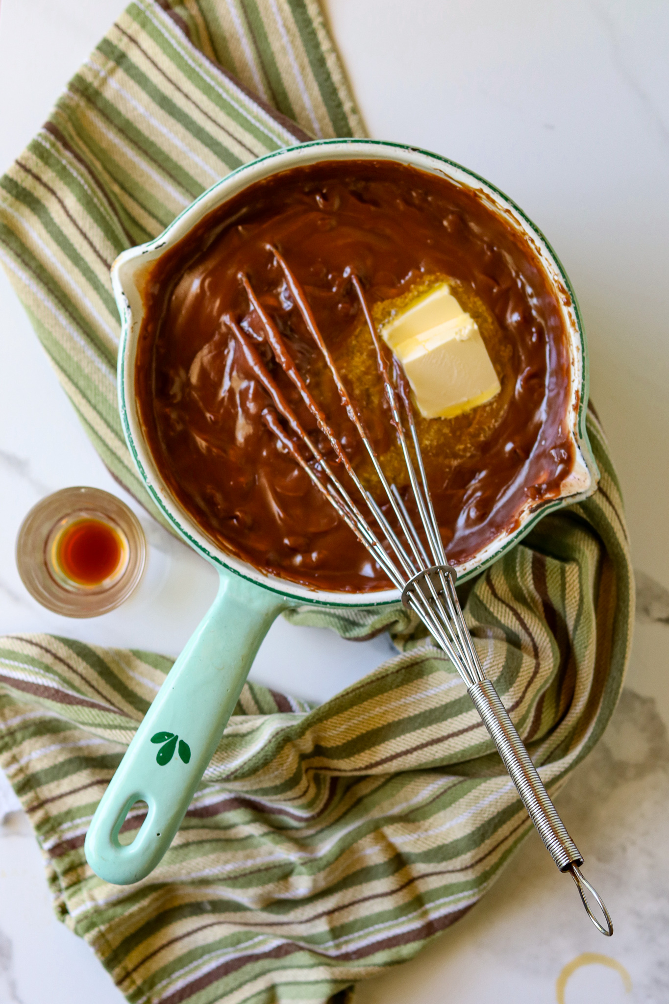 A saucepan with chocolate pie filling and a whisk.