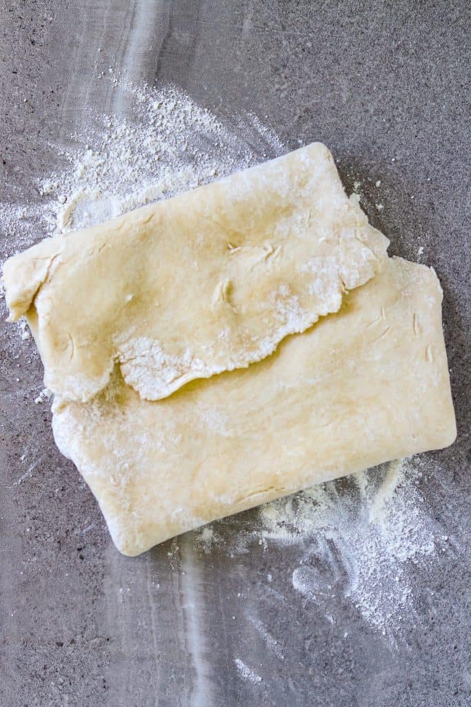 A folded pie crust on a flour-dusted counter.