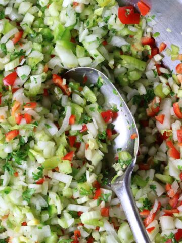 A bowl of chopped vegetables with a spoon in it.