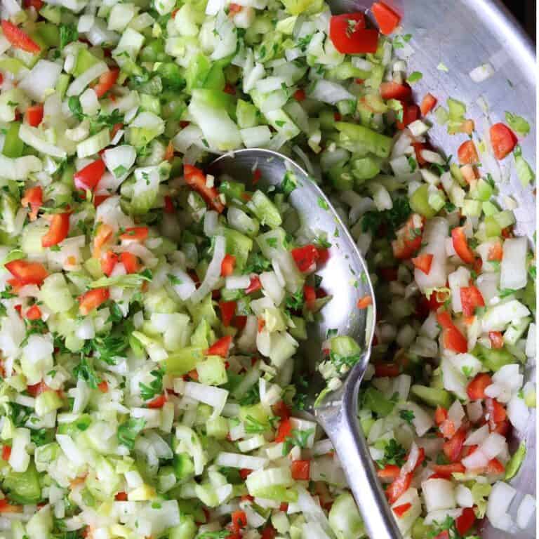 A bowl of chopped vegetables with a spoon in it.