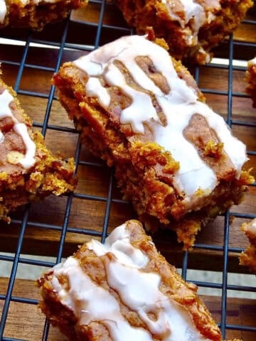Sliced, iced pumpkin bars on a black cooling rack.