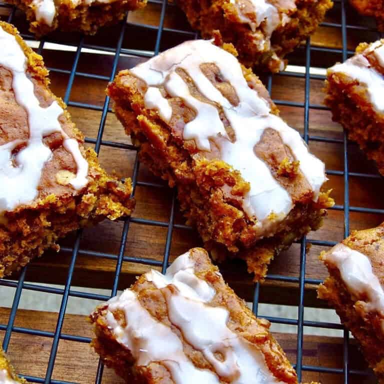 Sliced, iced pumpkin bars on a black cooling rack.
