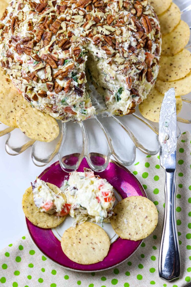 A Pineapple Cheese Ball on a glass plate with a spreader and a dish of cheeseball with crackers beside it.