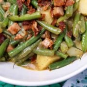 A bowl is full of smothered green beans with potatoes and ham.