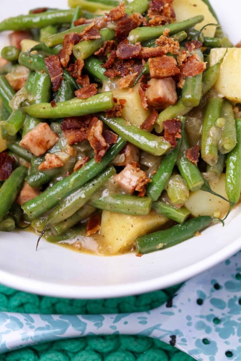 A bowl is full of smothered green beans with potatoes and ham.