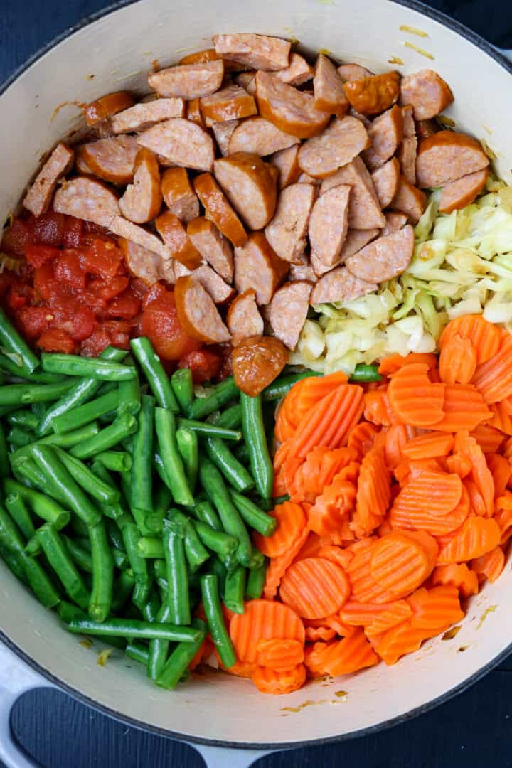A pot of different vegetables and sausage before they are stirred up to cook.