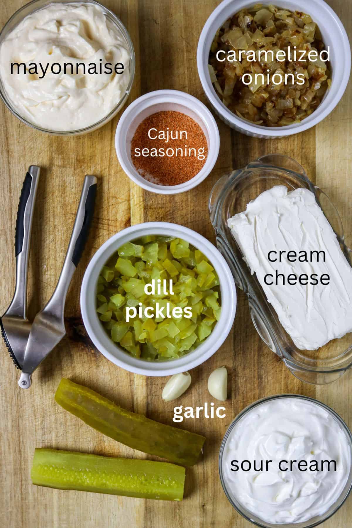 Ingredients of chopped pickles, seasoning, garlic, cream cheese, and cooked onions on a wooden board for Best Pickle Dip Recipe.