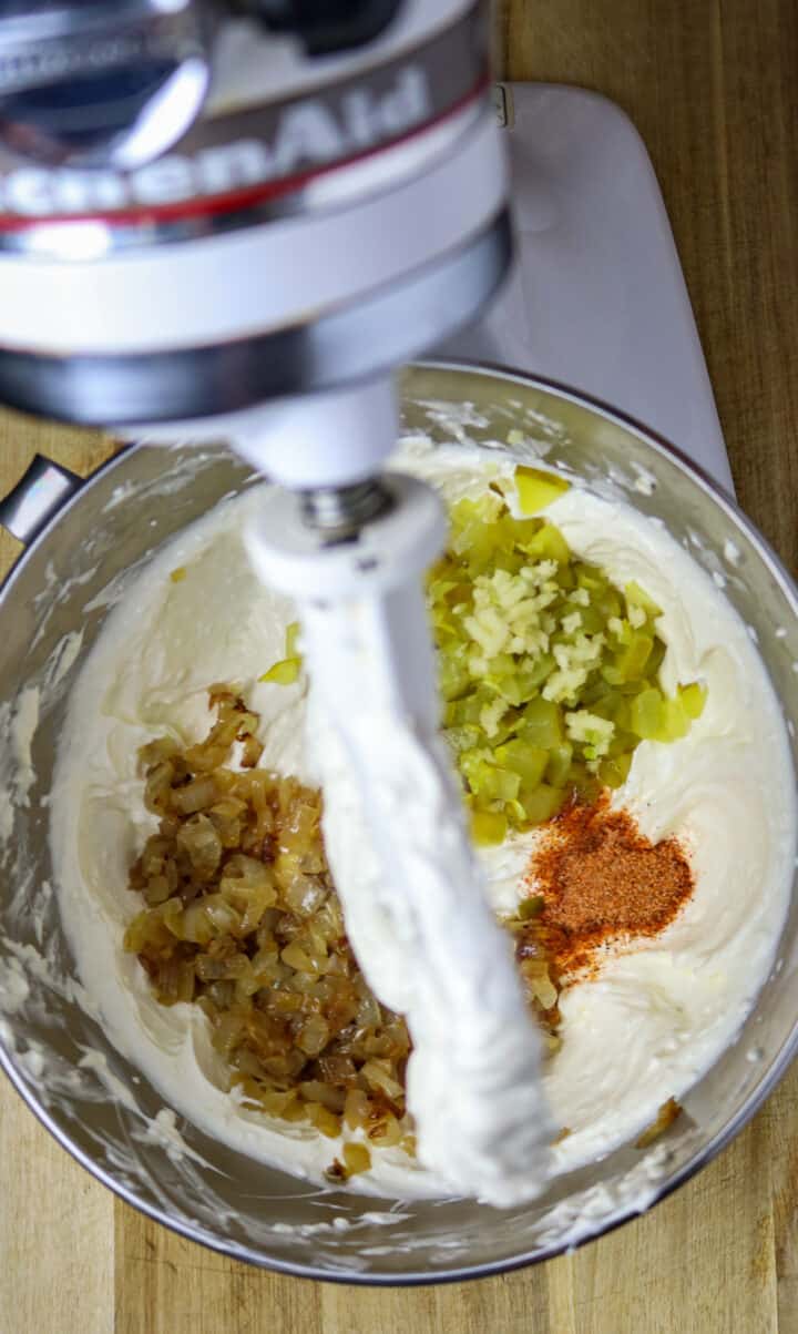 A stand mixer with ingredients for a dip in a silver mixing bowl.