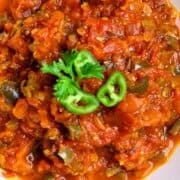 Roasted salsa with a garnish of parsley leaf and sliced jalapeno pepper.