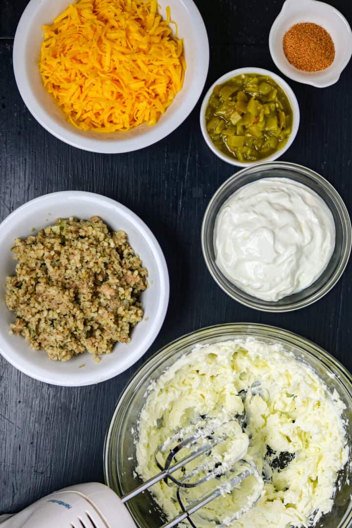 Bowls of cheese, seasoning, green chilis, sour cream, cream cheese, and boudin. 