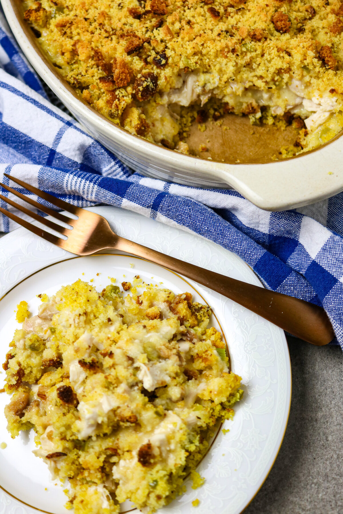 A pan of Easy Farmhouse Chicken Casserole next to a plate of it and a fork resting on the plate.