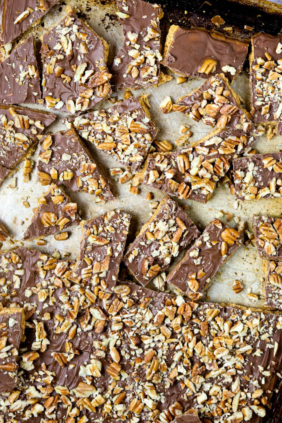 A sheet pan full of broken toffee pieces topped with nuts.