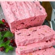 A loaf of frozen cranberry salad sliced with fresh cranberries and mint leaves.