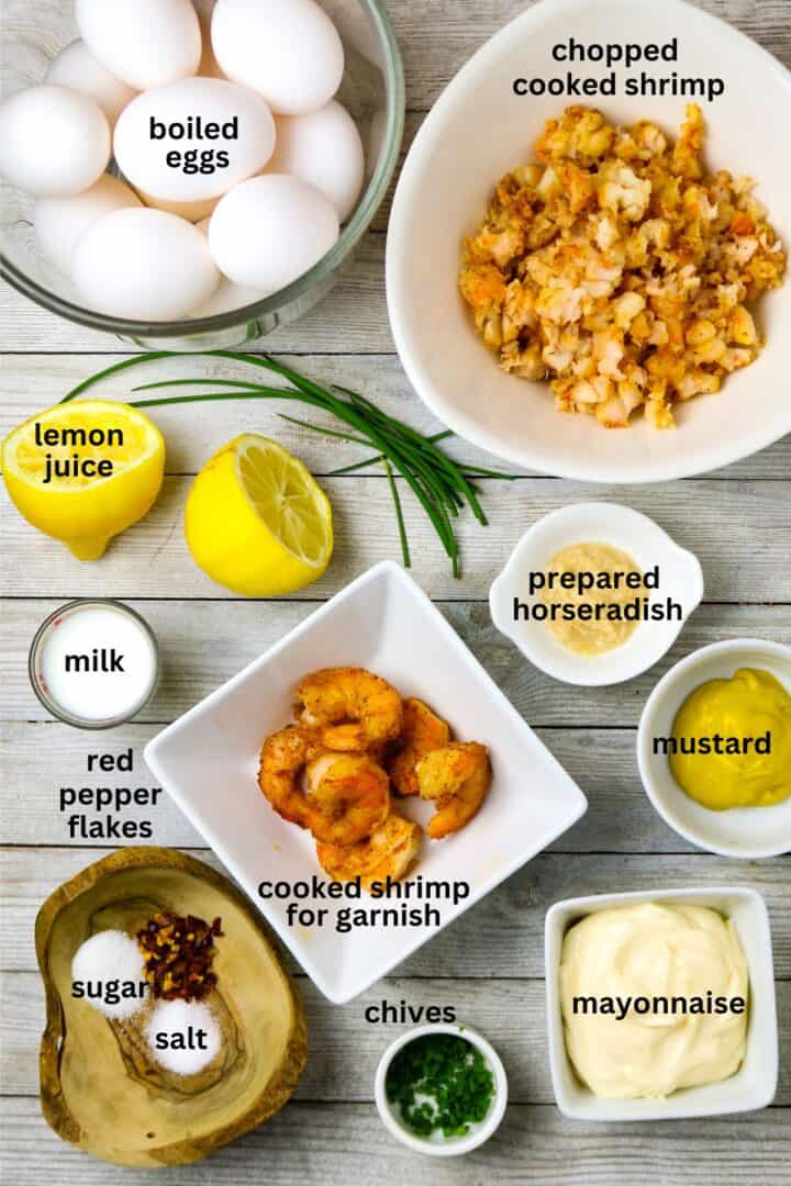 Boiled eggs, chopped shrimp, condiments, and seasonings for a stuffed egg recipe.