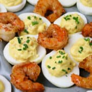 A dish of Cajun Shrimp Deviled Eggs garnished with cooked shrimp tails on top.