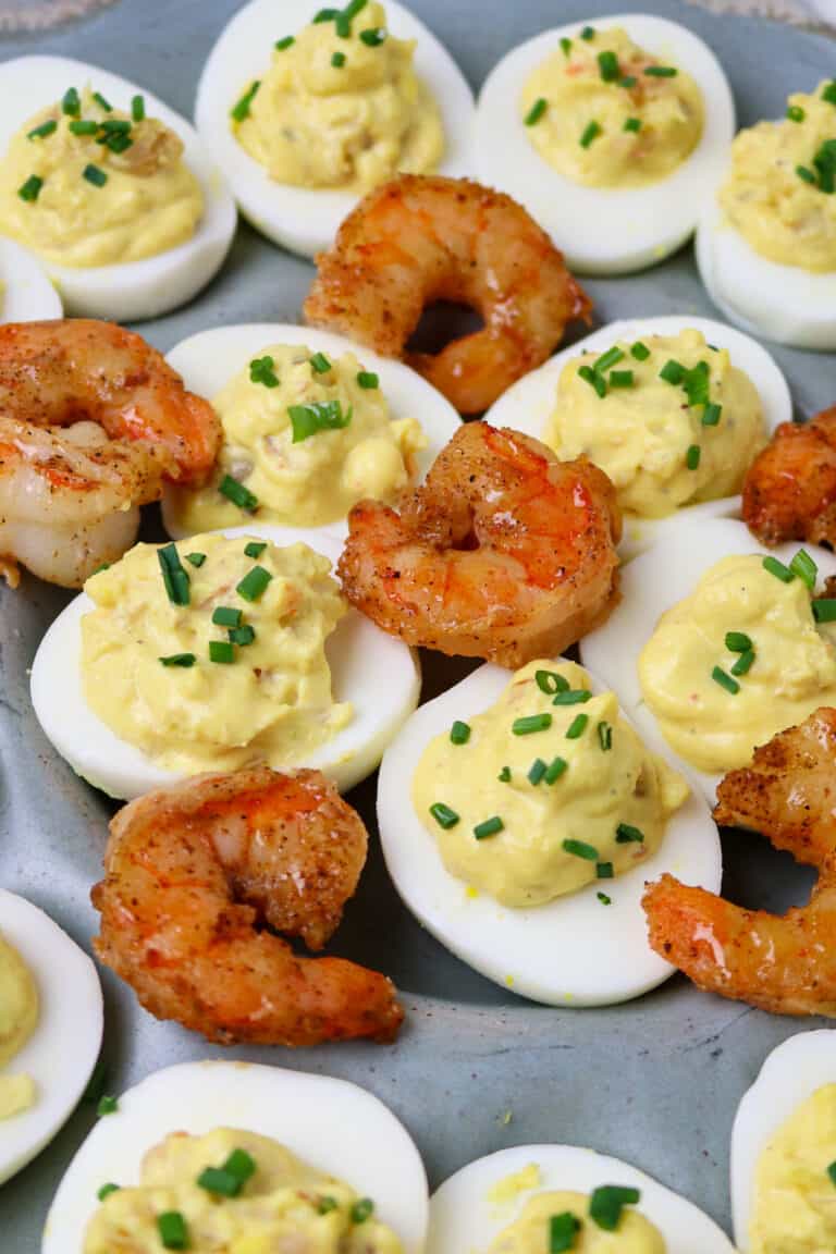 A dish of Cajun Shrimp Deviled Eggs garnished with cooked shrimp tails on top.