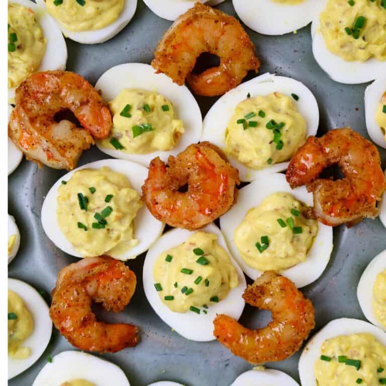 A dish of Cajun Shrimp Deviled Eggs garnished with cooked shrimp tails on top.
