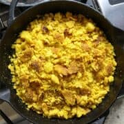 A black cast iron skillet filled with golden corn bread crumbles.