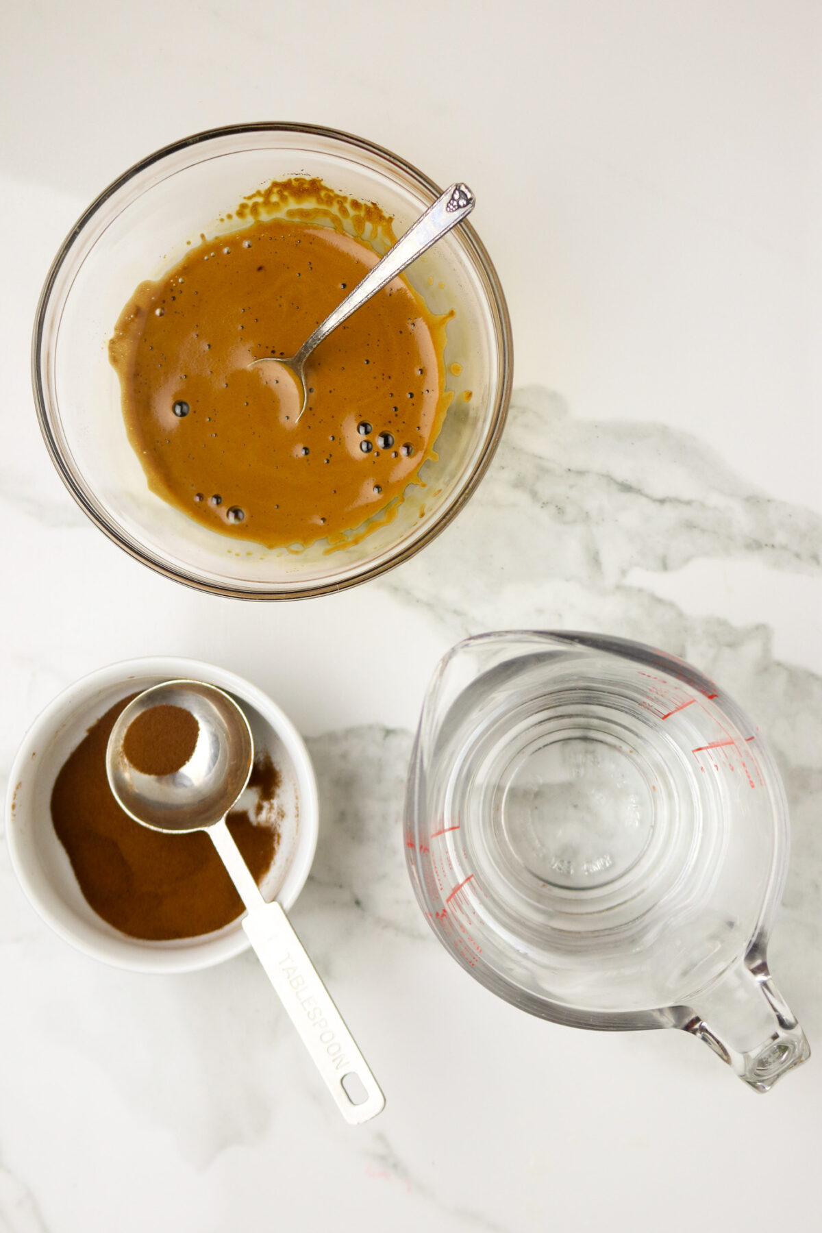 A bowl of coffee concentrate next to a bowl of Espresso powder and a cup of water.