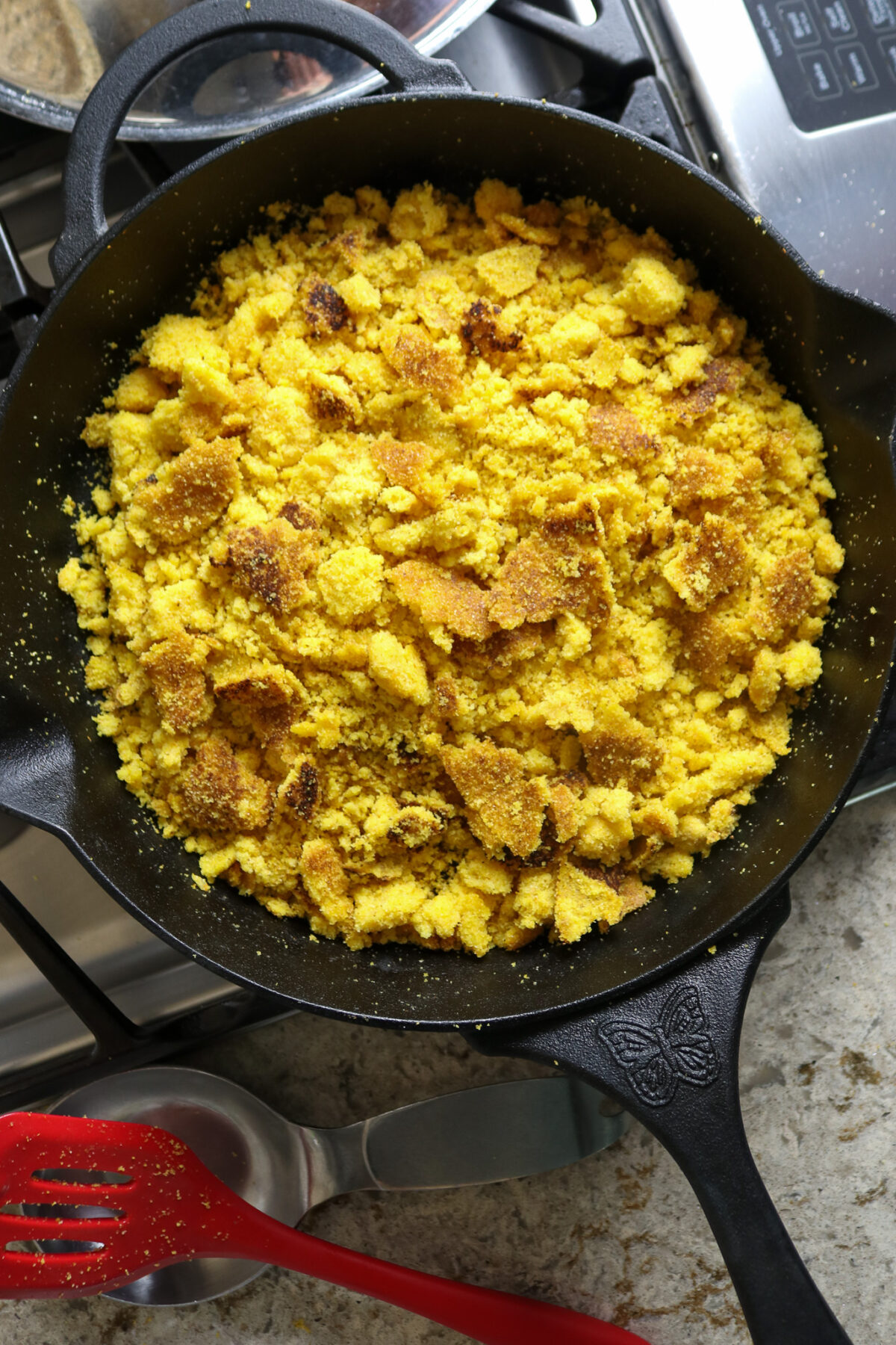 A black cast iron skillet filled with golden corn bread crumbles.