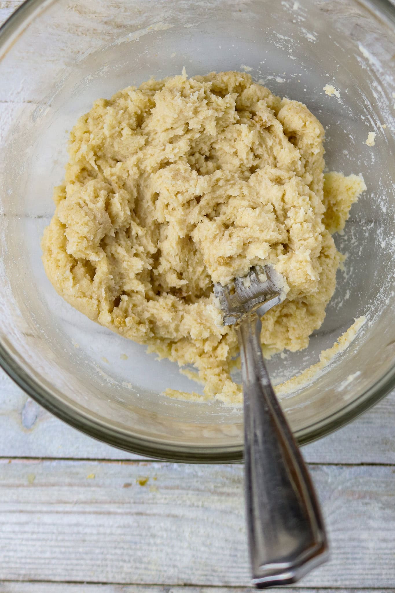 A glass bowl with a fork in a flour, butter, and sugar batter.