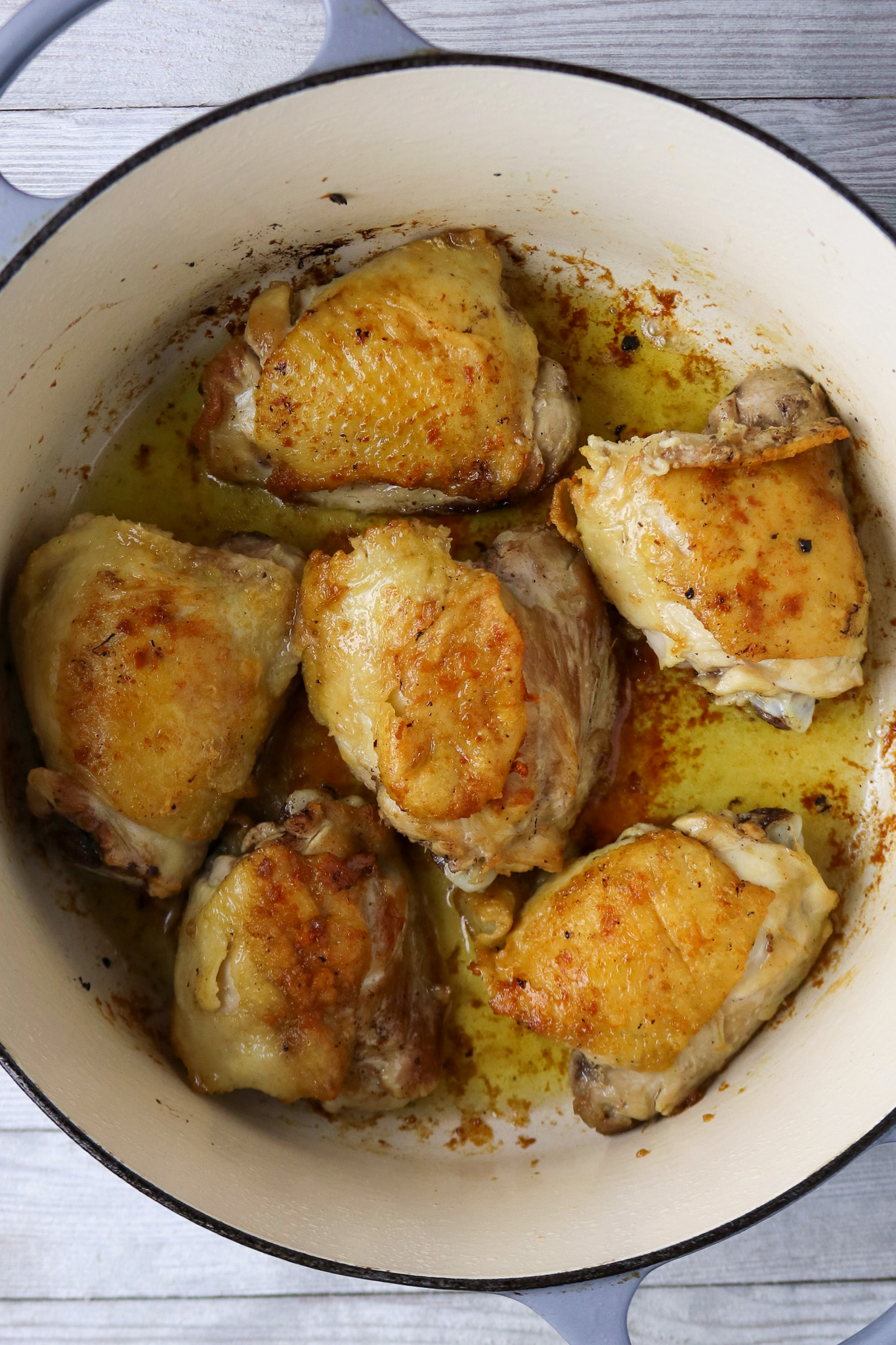 Six browned chicken thighs in a Dutch oven.