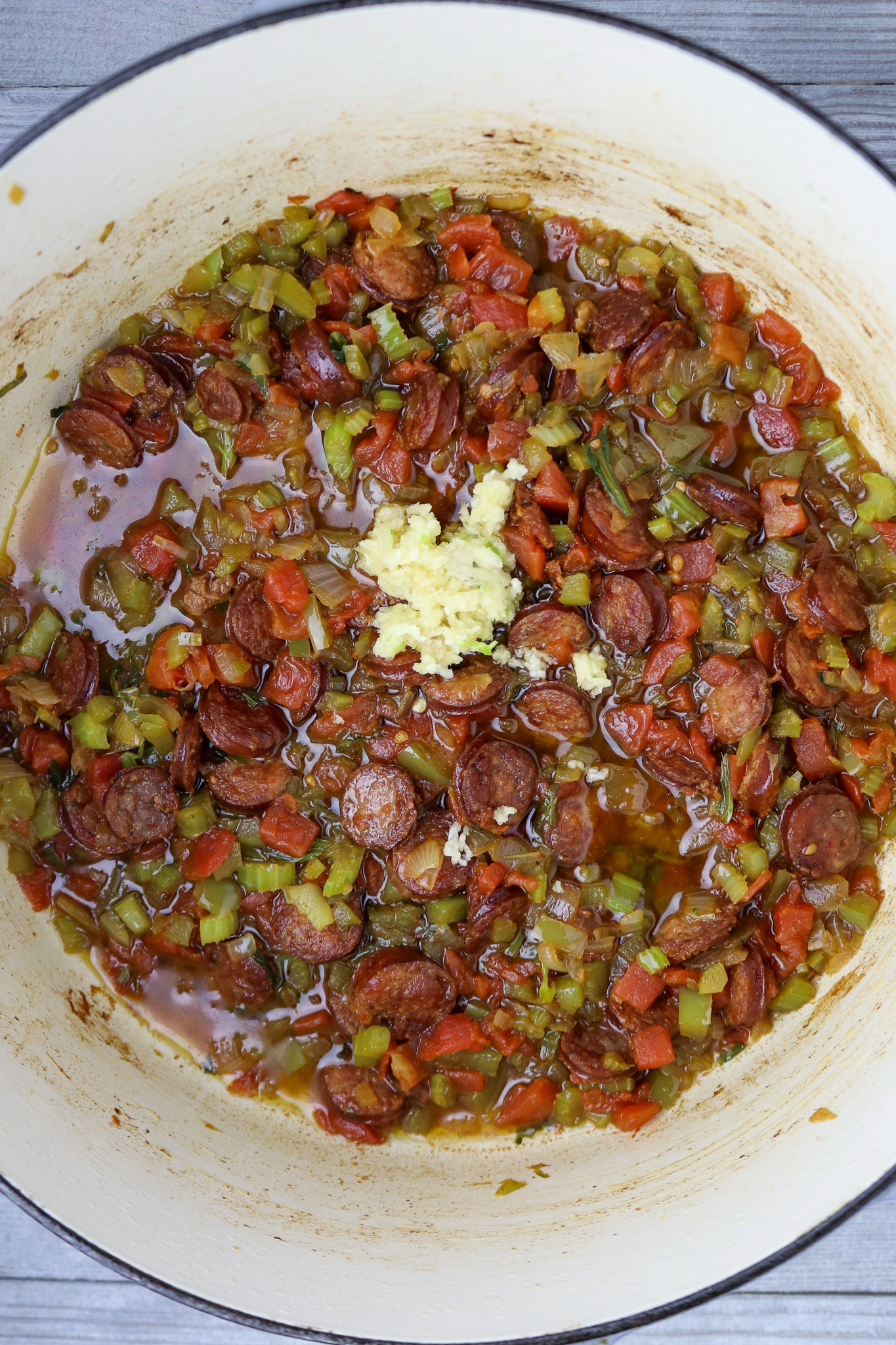 Cooked Cajun trinity vegetable sin a Dutch oven with minced garlic on top.