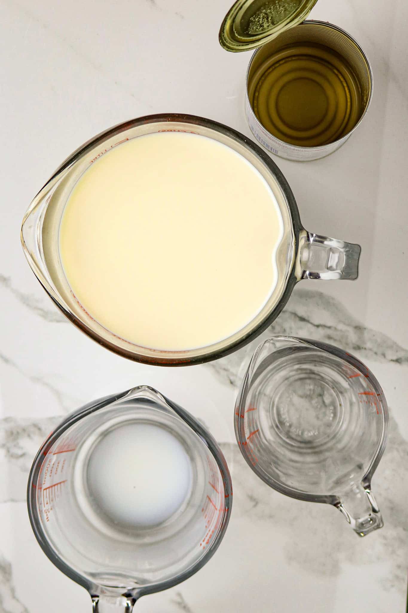 A 4-cup glass measuring cup filled with milk and empty containers beside it.