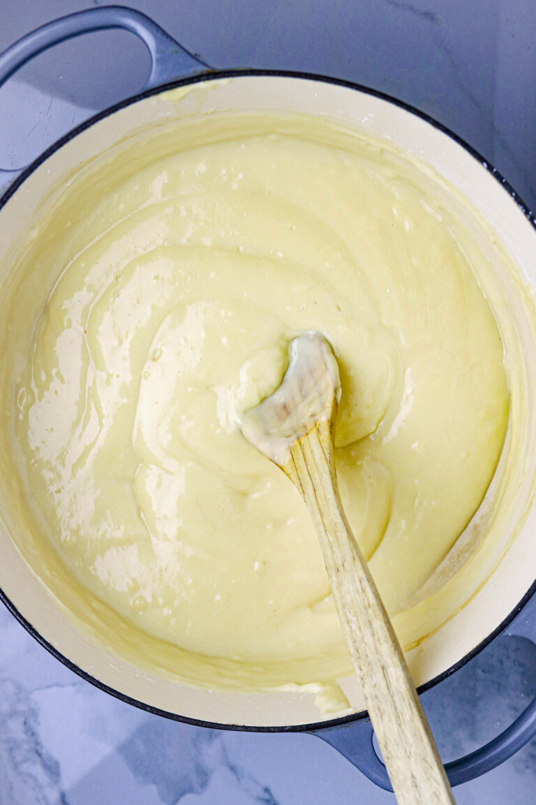 A Dutch oven filled with vanilla custard, la bouille recipe with a wooden spoon in the middle.