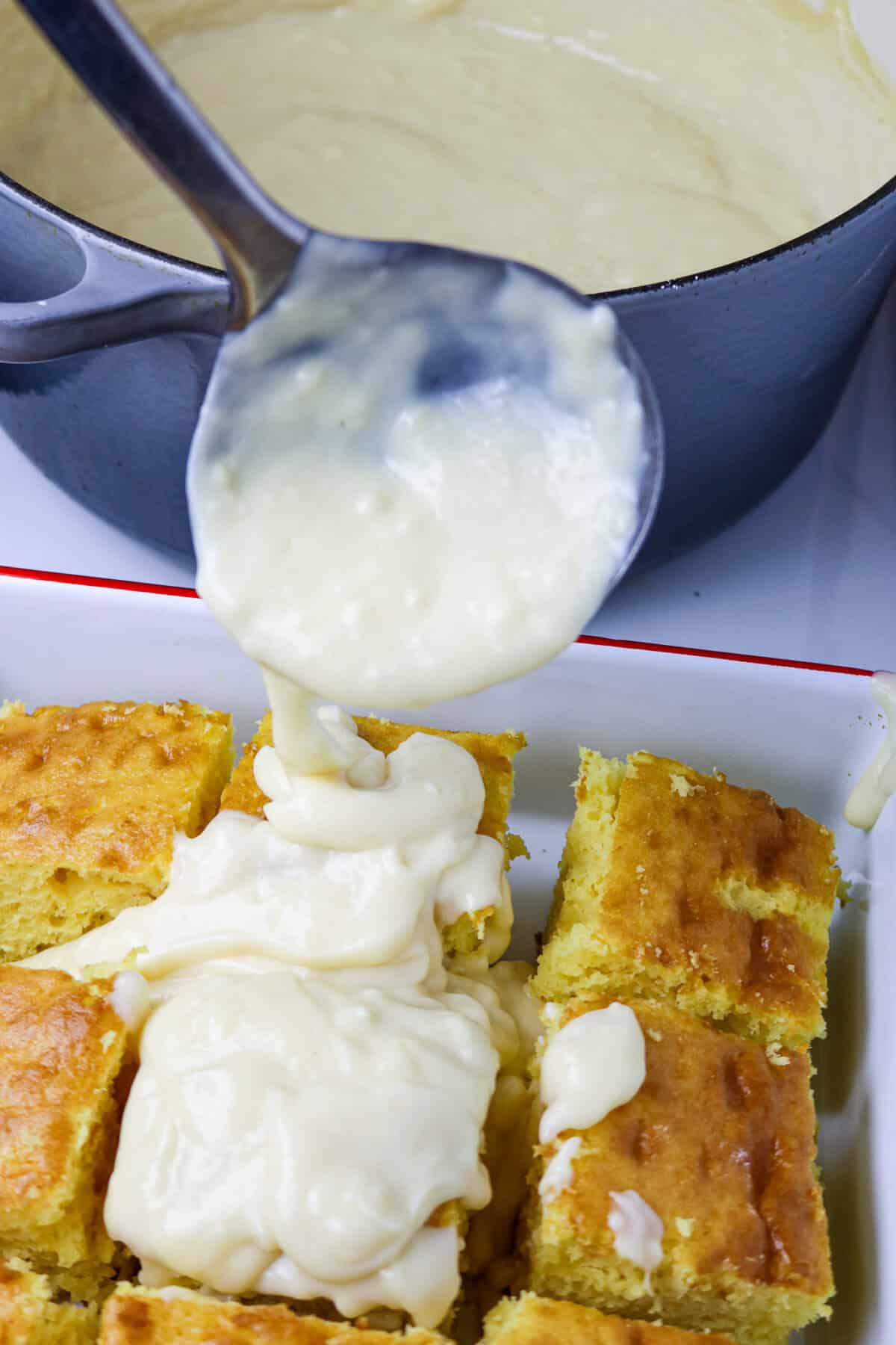 A pan of cake with a ladle spooning custard on top next to a pot of la bouille recipe.