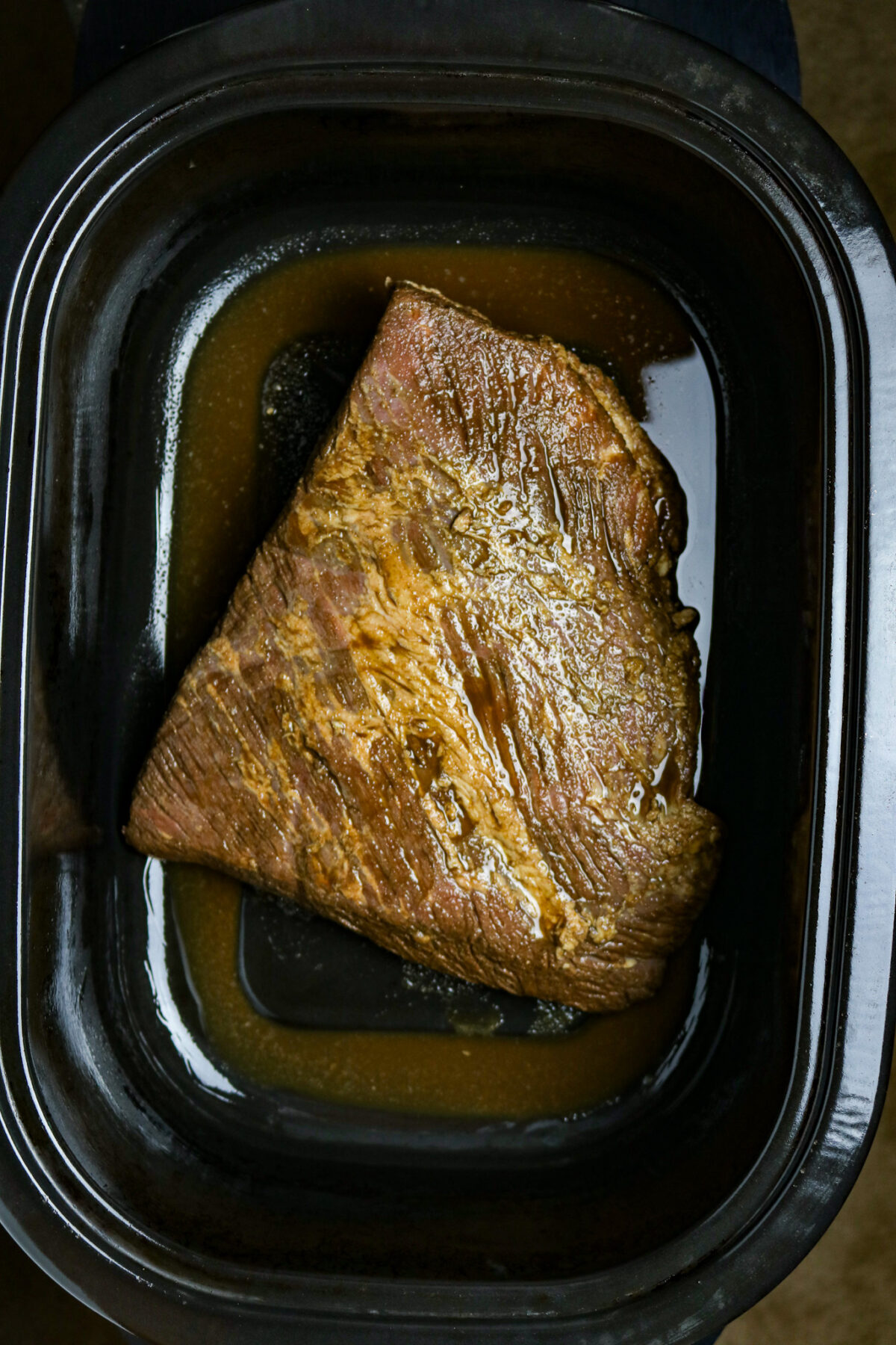A cooked beef brisket in a roasting pan.