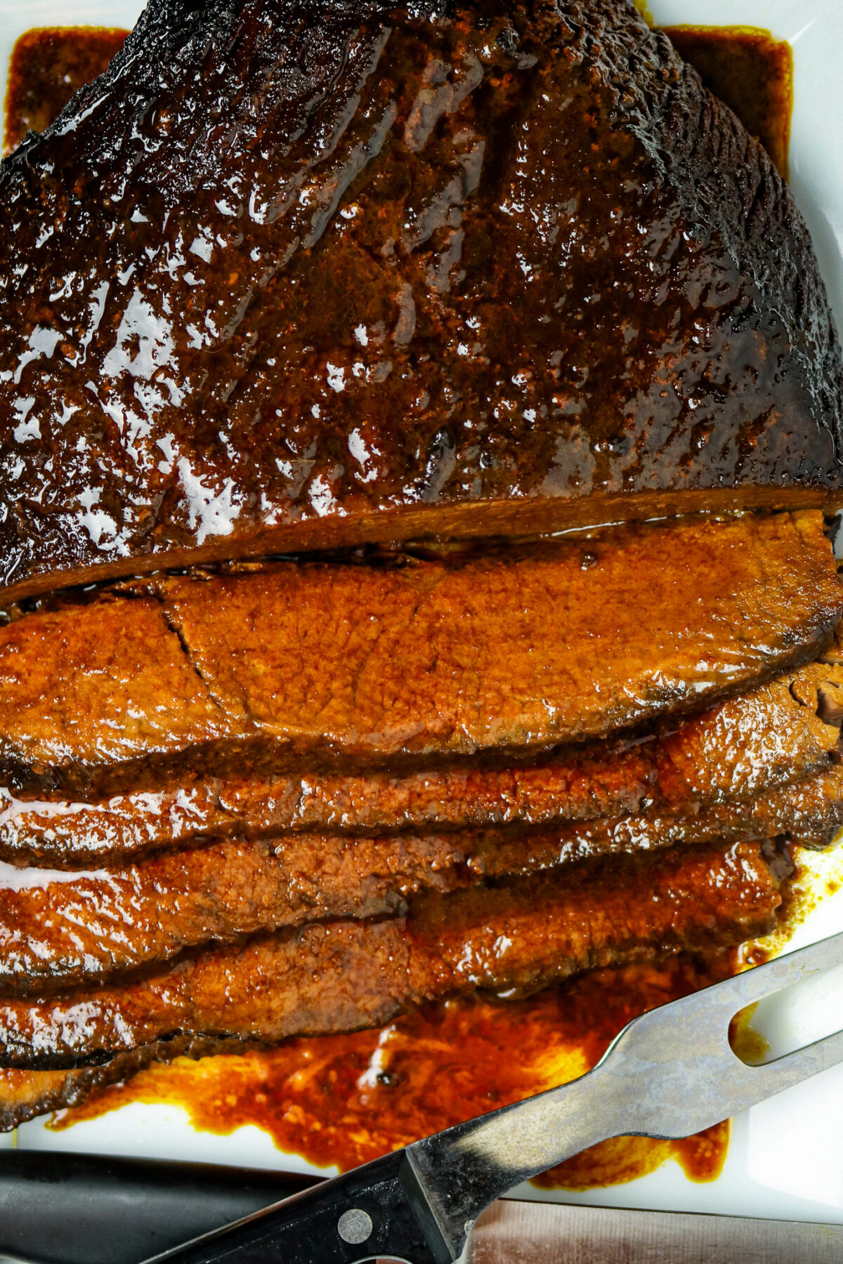 Sliced brisket with bbq sauce on it with a fork next to it.
