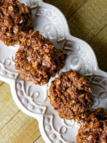 A row of four chocolate fudgy cookies on a light gray scalloped platter.