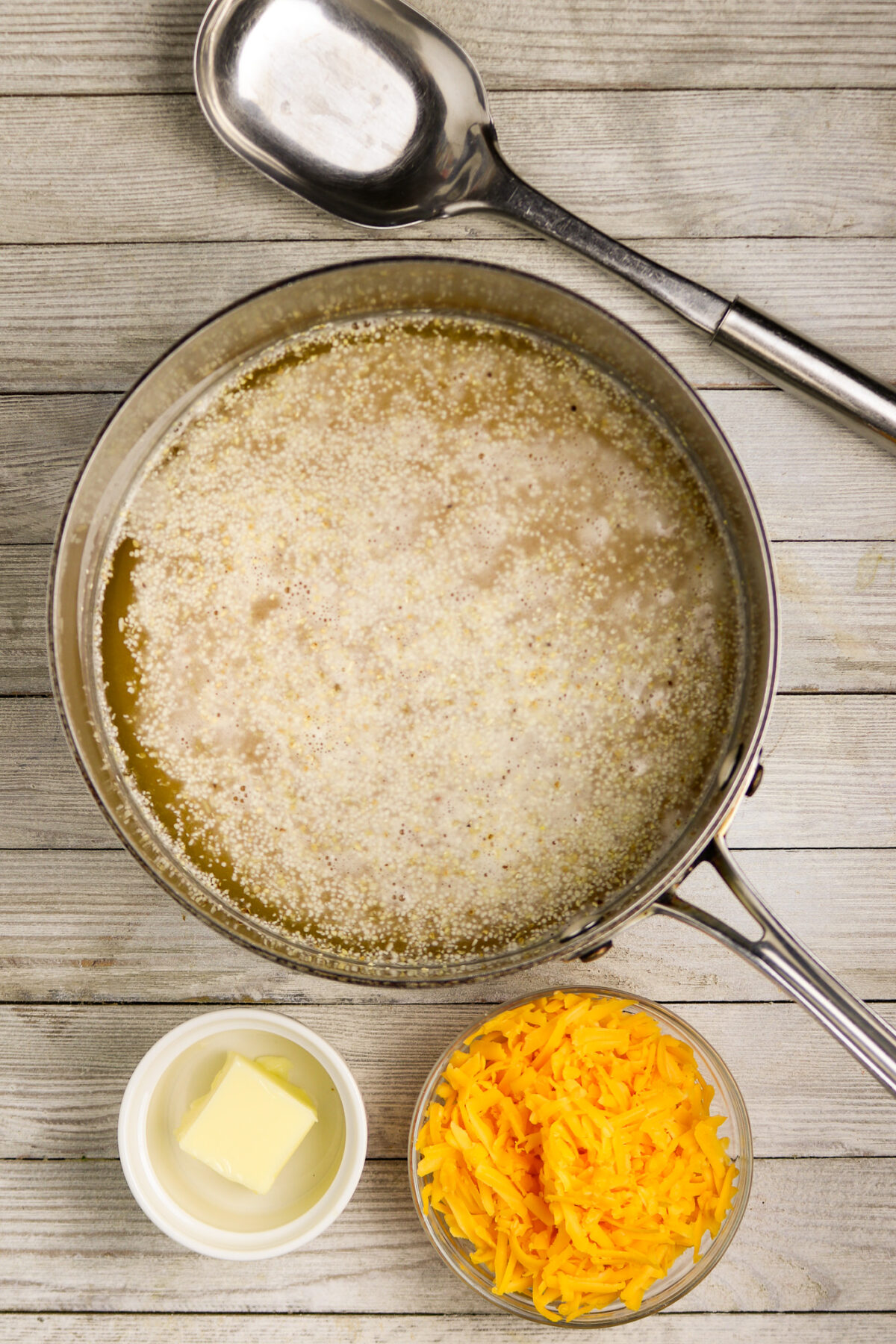 A pot of grits with butter and cheese beside it.