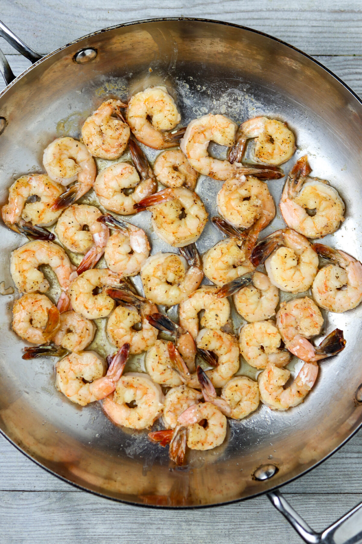 Sauteed shrimp in a pan with tails for shrimp and grits.