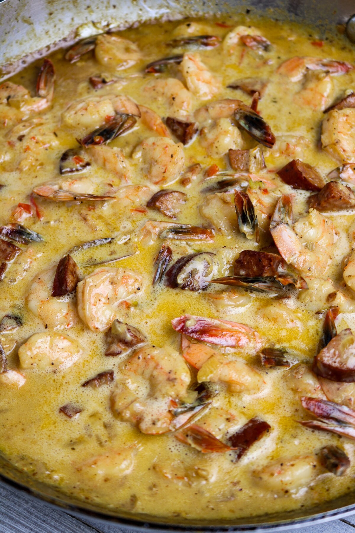 Shrimp and sausage in a creamy sauce in a pan.