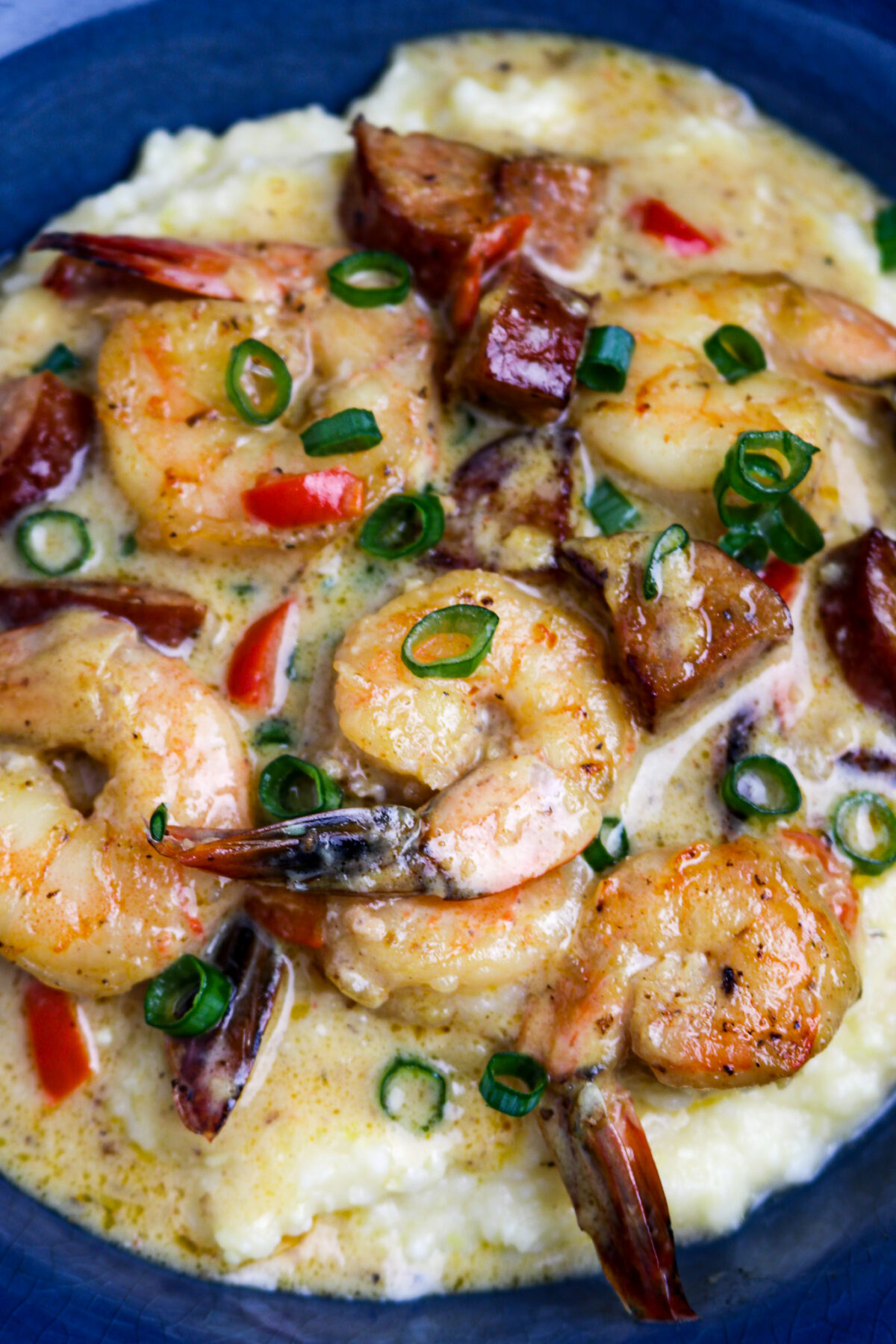 A blue bowl of Cajun Shrimp and Grits Recipe with Andouille Sausage.